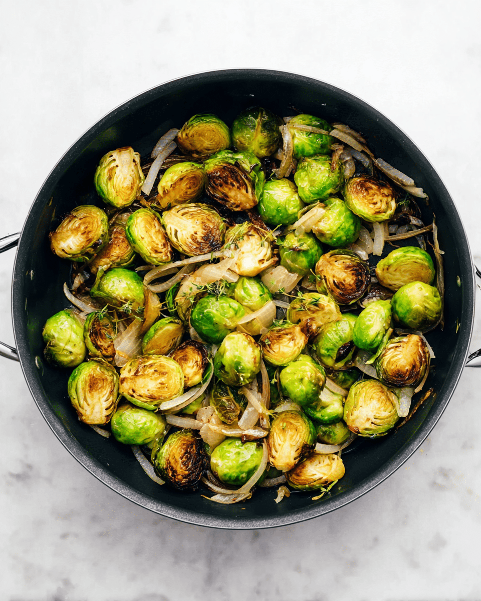 A black round pan filled with roasted Brussels sprouts and sliced onions. The Brussels sprouts are whole and halved, showing a mix of green and golden-brown colors with some charred spots. Thin slices of white onions are spread throughout the pan, adding a light, translucent layer among the sprouts. The pan is placed on a white marbled surface. photo taken with an iphone --ar 4:5 --v 7