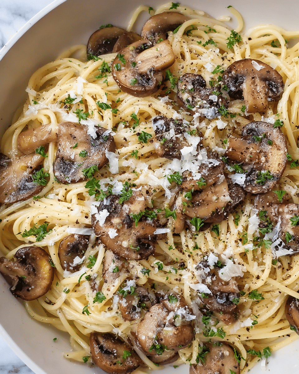 The image shows a close-up of a dish with thin, pale yellow spaghetti noodles forming the base layer. On top, there are several medium-brown sautéed mushroom slices scattered evenly across the noodles. The mushrooms have a slightly glossy texture with darker edges. Finely grated white cheese is sprinkled sparsely over the pasta and mushrooms, adding small white flecks throughout. Tiny green parsley pieces are dotted across the whole dish. A light dusting of black pepper is visible on top, giving a speckled effect. The dish is placed on a white plate against a white marbled surface. Photo taken with an iphone --ar 4:5 --v 7