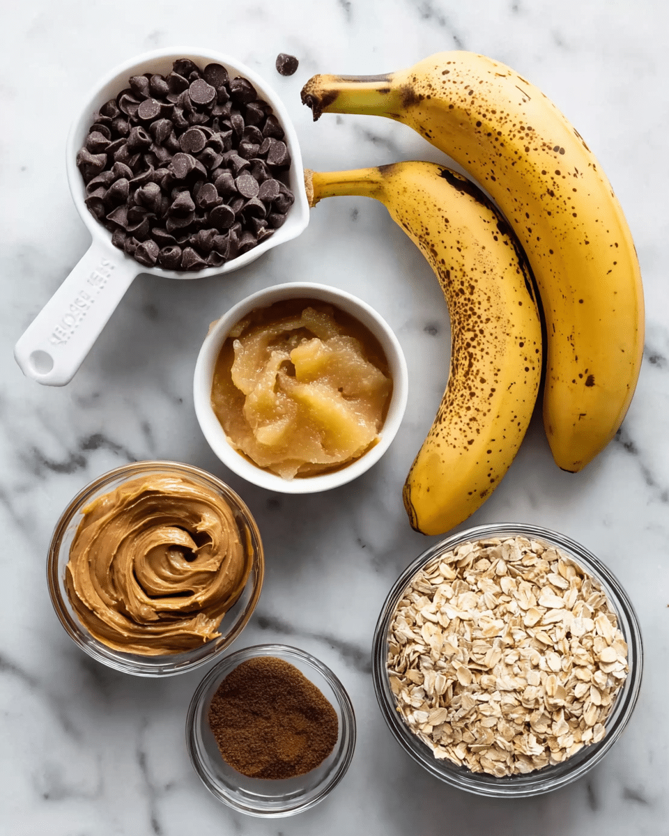 The image shows several ingredients on a white marbled surface, ready to make a recipe. There are two ripe yellow bananas with brown spots placed side by side. On the left, a white measuring cup is filled with dark brown chocolate chips. Next to it, a small white bowl holds light yellow applesauce with a smooth texture. Below these items, a small clear bowl contains smooth, light brown peanut butter with some swirls on top. Near the peanut butter, two black measuring cups sit side by side; one is filled with dark brown flax seeds and the other with light brown oat flakes. A larger clear bowl filled with pale rolled oats is placed to the right. Photo taken with an iphone --ar 4:5 --v 7