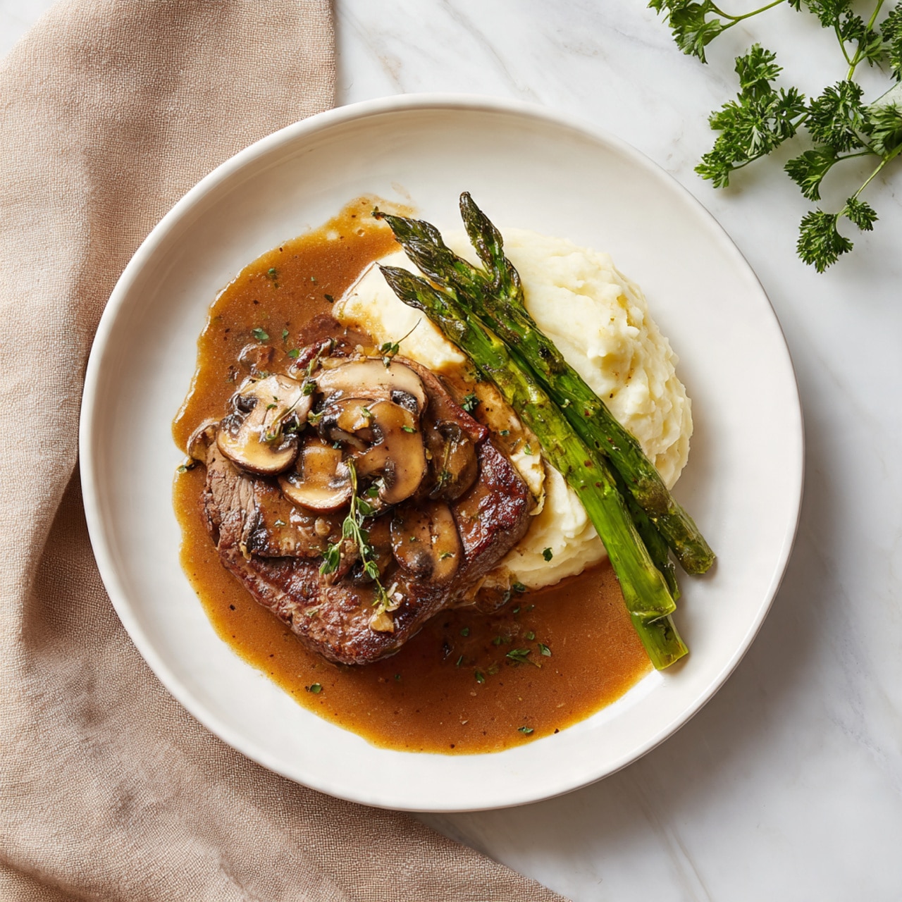 The dish shows one thick, golden brown piece of cooked meat layered at the bottom center of a white plate. On top of the meat, there are several cooked brown mushroom slices and some bright green asparagus spears placed diagonally. A rich brown gravy with specks of herbs covers the meat and mushrooms, slightly spreading onto the plate. To the right side of the plate, there is a creamy mound of white mashed potatoes with some gravy pooled on top. The plate sits on a white marbled surface with a soft beige cloth and some green parsley in the background. Photo taken with an iphone --ar 4:5 --v 7