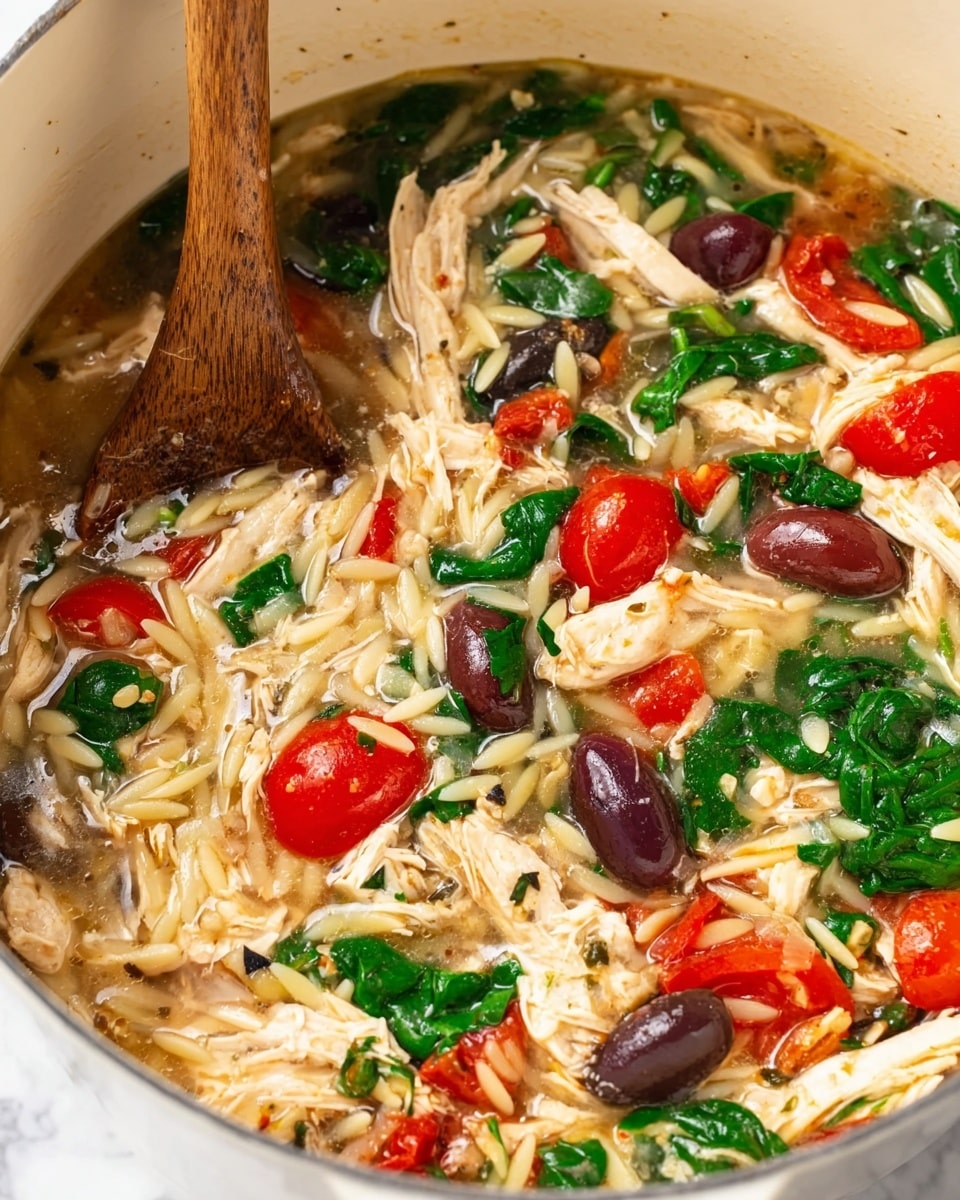 This close-up image shows a mix of shredded white chicken pieces, small orzo pasta, dark purple black olives cut in half, bright green spinach leaves, and halved red cherry tomatoes all combined in a light brown broth. The ingredients are inside a white pot with a visible wooden spoon stirring the mixture on the left side. The textures include soft chicken, smooth olives, tender spinach, juicy tomatoes, and slightly firm pasta, creating a colorful and fresh look against the white pot and white marbled background. Photo taken with an iphone --ar 4:5 --v 7