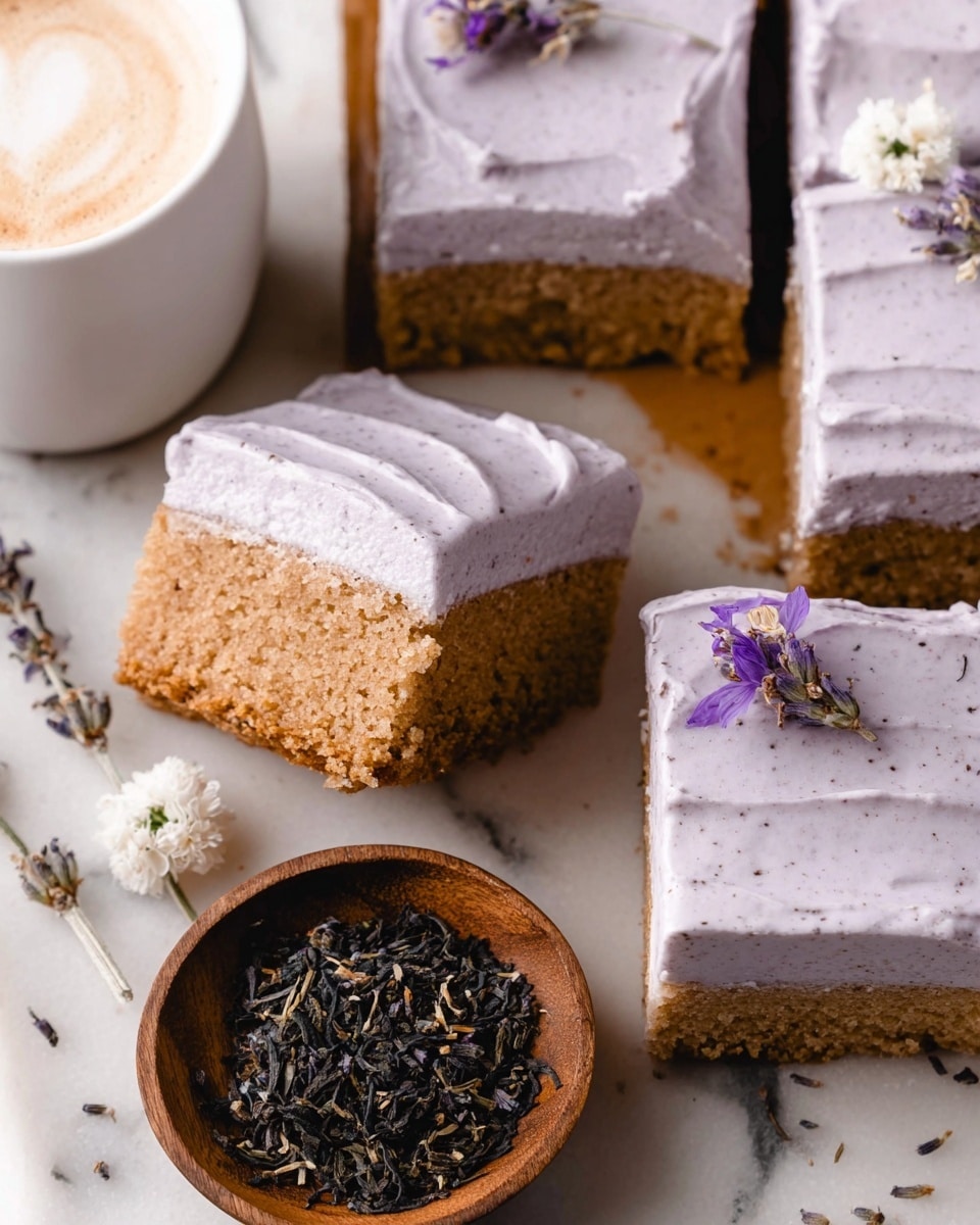 The image shows several square pieces of cake with one piece lifted slightly, revealing two layers: a light brown, moist cake layer at the bottom and a thick, pale lavender-colored frosting layer on top. Some cakes have tiny dark specks on the frosting, and one piece is decorated with a small white flower and a few light purple dried flowers. Next to the cakes, there is a white cup filled with frothy coffee, and a small wooden bowl containing black tea leaves with dried lavender flowers. All items rest on a white marbled surface. Photo taken with an iphone --ar 4:5 --v 7