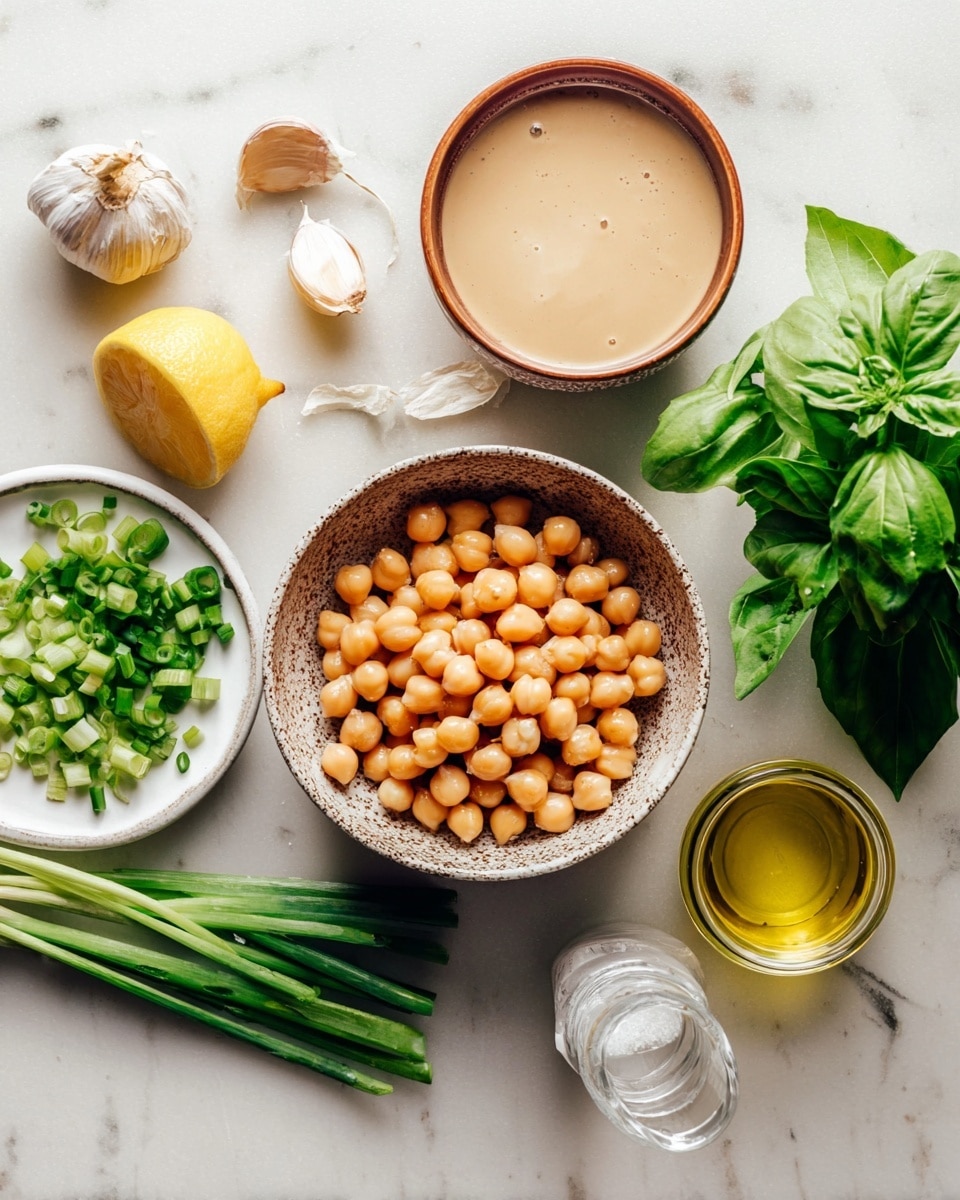 The image shows a close-up of cooking ingredients arranged on a white marbled surface. In the center, there is a single brown speckled bowl filled with soaked chickpeas in light brown liquid. Above it is a small round brown bowl with a creamy beige sauce, next to some fresh green basil leaves and parsley on the right. On the left side, there is a white plate holding chopped green onions and a lemon half with bright yellow skin. A single peeled garlic clove and a spoon with coarse salt are placed above the plate. To the right of the chickpeas, there is a small white bowl filled with golden olive oil and a clear small glass jar with white liquid. A large basil leaf lies on the marble surface below the plate. The setup looks fresh and natural, with soft light and simple colors. photo taken with an iphone --ar 4:5 --v 7