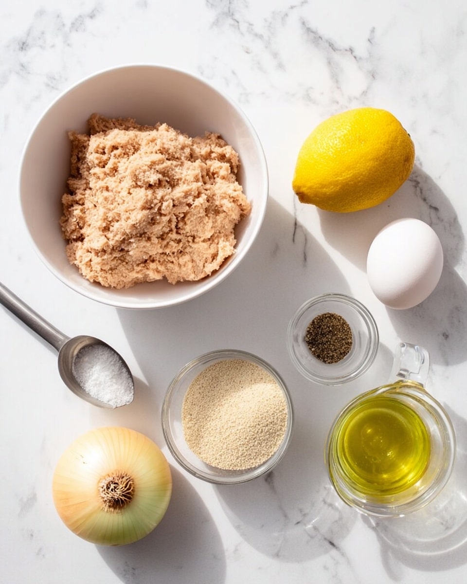 The image shows a white bowl filled with light brown mashed tuna on the left side. Around it are six ingredients placed on a white marbled surface: a yellow onion with a bit of brown skin on top, a bright yellow lemon, a whole white egg, a small clear glass bowl with black pepper, a clear plastic container with beige breadcrumbs, and a metal measuring cup with light yellow oil. The ingredients are spaced neatly with soft natural light. Photo taken with an iphone --ar 4:5 --v 7