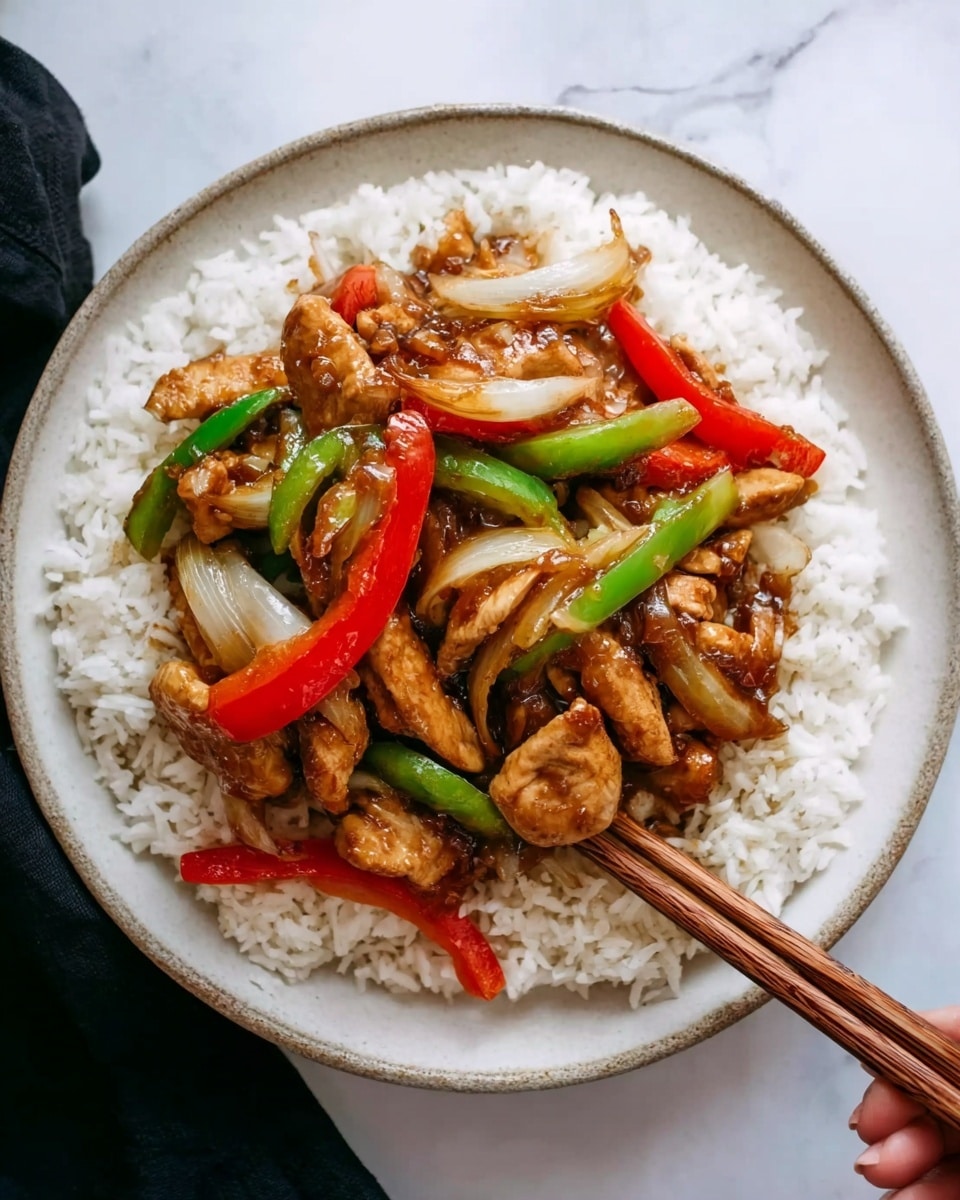 A white round plate holds a bed of fluffy white rice, topped with several pieces of cooked brown chicken that have a slightly shiny texture from sauce. There are long slices of cooked onion, red bell pepper strips, and green bell pepper strips mixed evenly with the chicken. The colors contrast well with the white rice, showing warm brown, bright red, and vibrant green. The plate is placed on a white marbled surface. A pair of wooden chopsticks rest on the plate's edge, and a woman's hand is holding one of the chopsticks near the bottom right of the image. Photo taken with an iphone --ar 4:5 --v 7