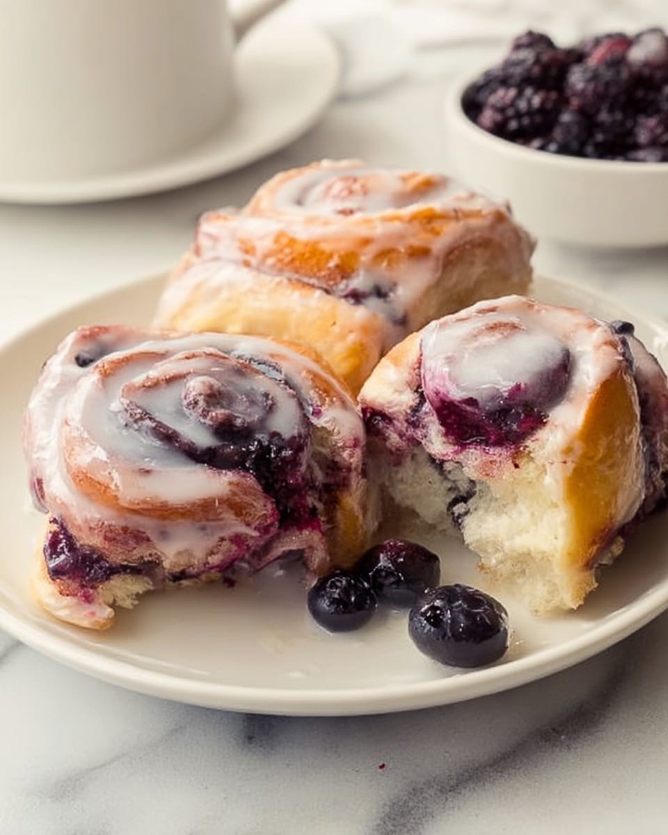 The image shows three pieces of sweet rolls with a swirl shape on a white plate. The rolls have a soft, golden-brown outer layer with visible swirls of dark purple berries inside. Each roll is coated with a shiny, white glaze that covers the top and drips slightly down the sides. One roll reveals a bite, showing its fluffy inside and the layers of dough mixed with berries. There are loose berries on the plate around the rolls. The plate sits on a white marbled surface, and in the background, there is a white bowl filled with dark berries. Photo taken with an iphone --ar 4:5 --v 7