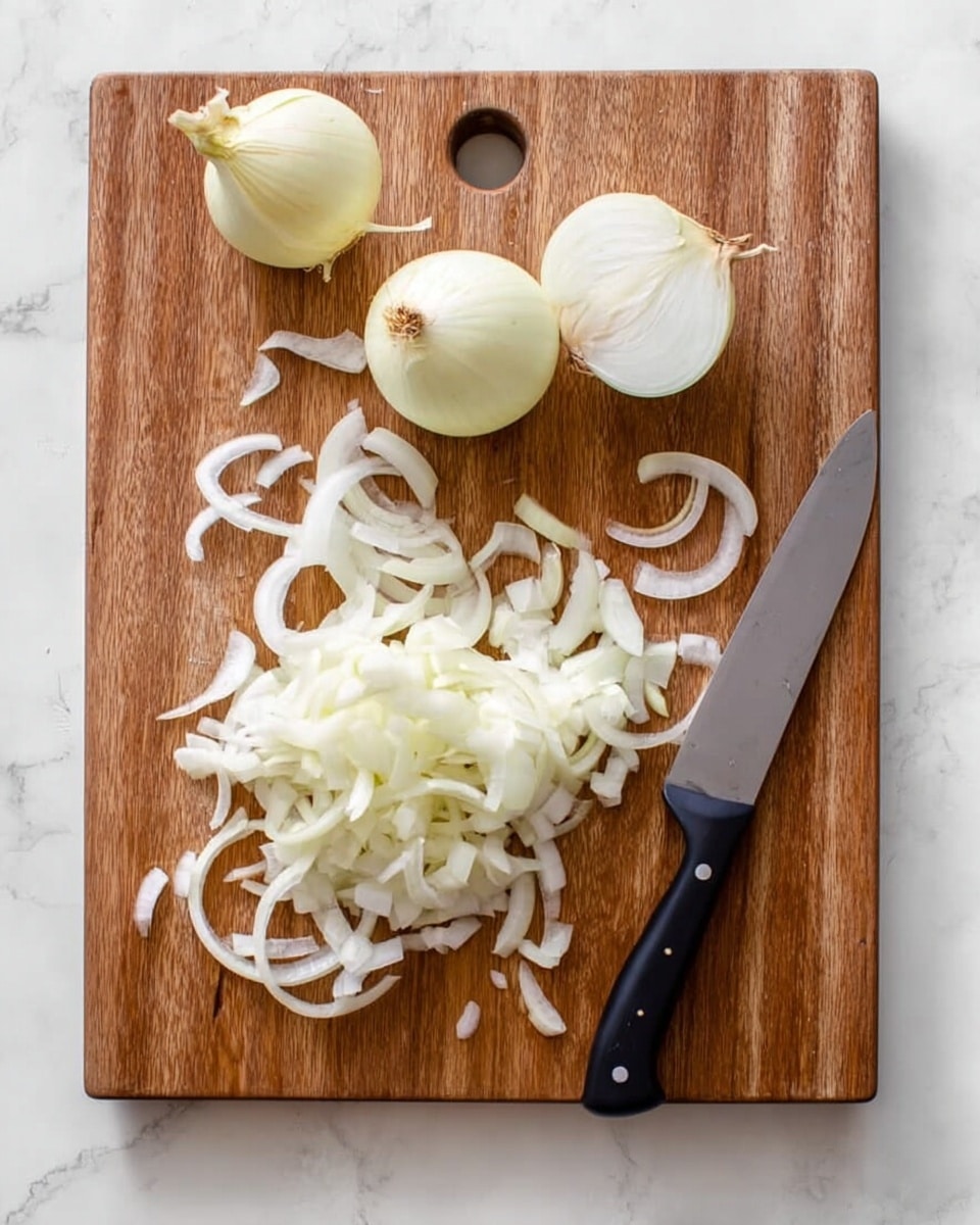A wooden cutting board placed on a white marbled surface holds two peeled onions at the top, one partially sliced onion, and a pile of thin white onion slices arranged mostly on the left side. On the right side of the board, there is a large sharp silver knife with a black handle resting horizontally, surrounded by some scattered onion slices. The overall scene is bright and clean with soft natural light. photo taken with an iphone --ar 4:5 --v 7