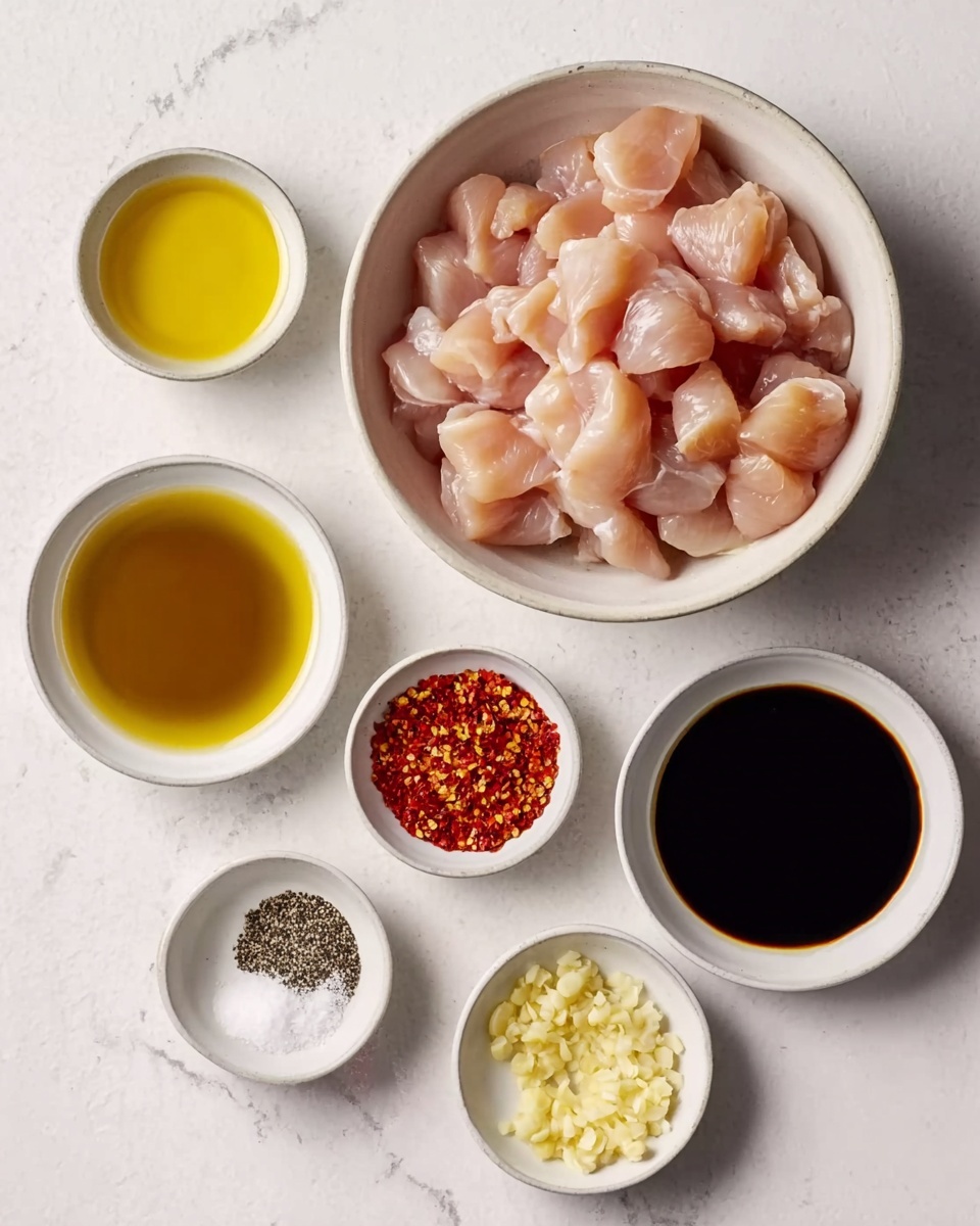The image shows a top view of seven small white bowls arranged on a white marbled surface. The largest bowl at the top center holds many pieces of raw, light pink chicken, cut into small chunks. Below to the left is a bowl with clear golden oil, and next to it on the right is a bowl with dark soy sauce. Below these two, in the middle, are three smaller bowls: one with red chili flakes, one with mixed white salt and black pepper, and another with finely chopped pale yellow garlic. The composition is neat and clear, focusing on the ingredients for a cooking recipe. Photo taken with an iphone --ar 4:5 --v 7