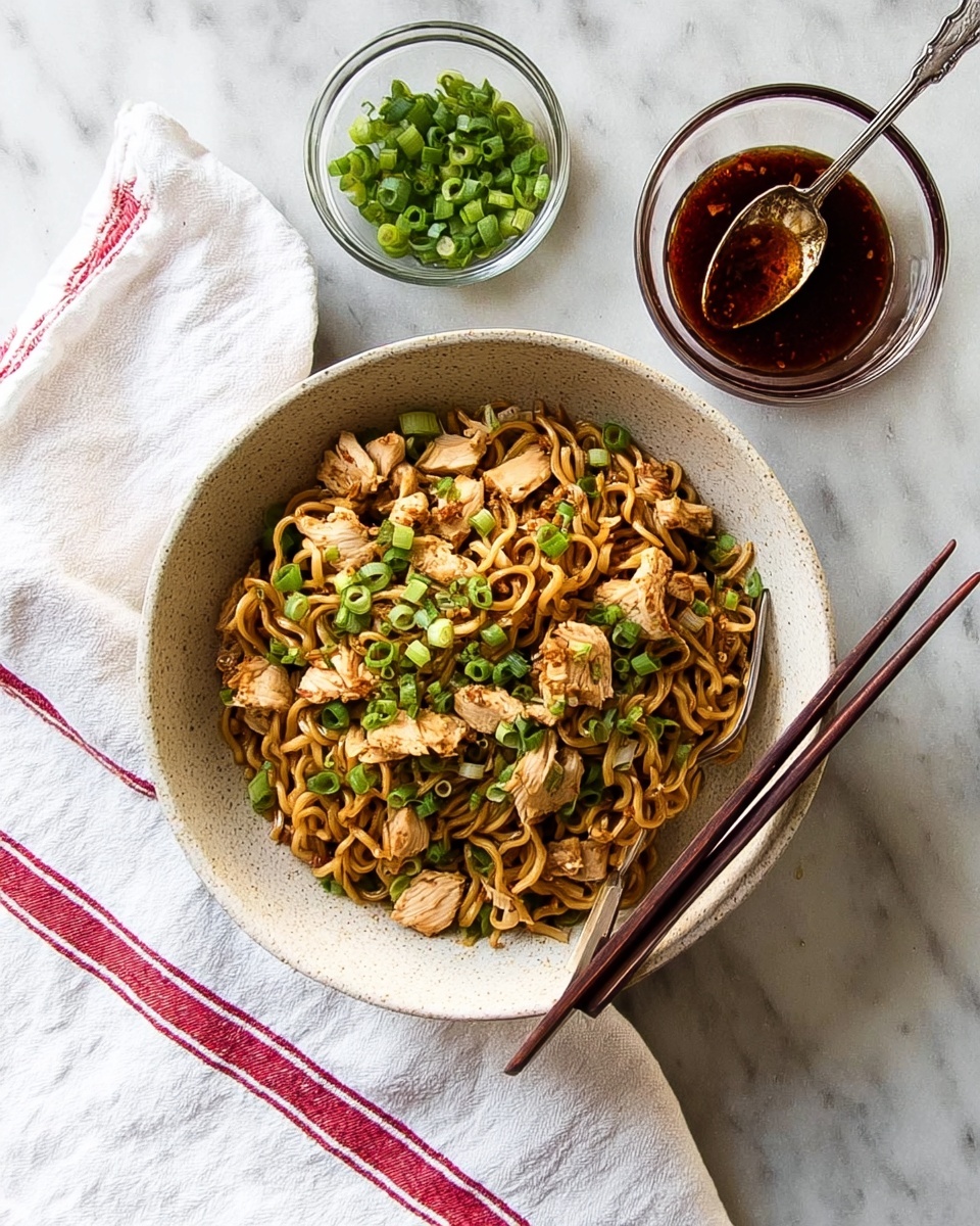A white speckled bowl filled with cooked curly noodles mixed with small pieces of light brown cooked chicken and green chopped scallions scattered on top. The bowl rests on a white cloth with red stripes, placed on a white marbled textured surface. Two dark brown chopsticks lay on the right edge of the bowl. Above the bowl, there is a small clear glass bowl with more chopped green scallions and another clear glass bowl with a dark reddish sauce, holding a silver spoon. photo taken with an iphone --ar 4:5 --v 7