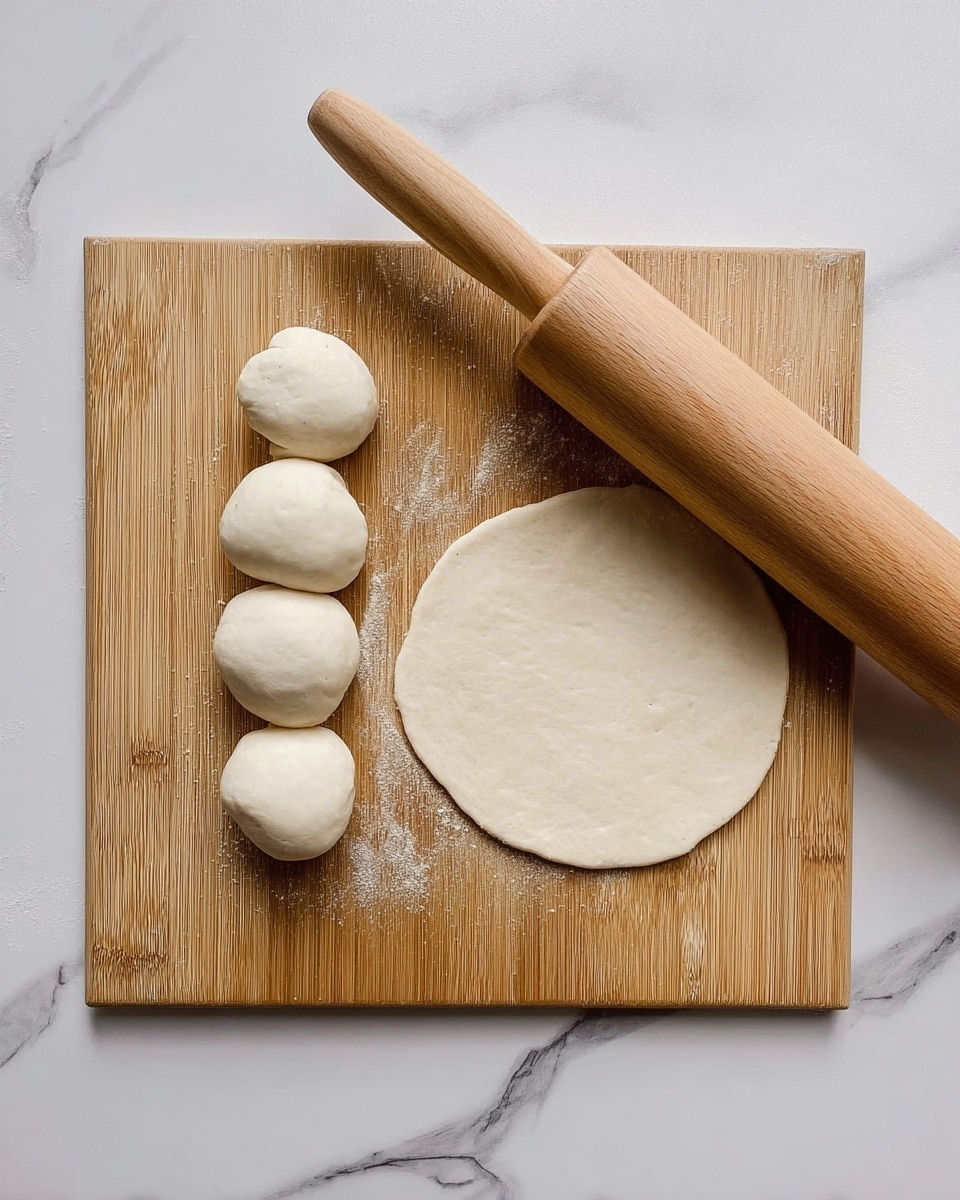 The image shows a wooden board on a white marbled surface. On the board, there are four small white dough balls lined up vertically on the left side. To the right of these balls, one dough ball is rolled flat into a round, thin circle. A wooden rolling pin lies diagonally across the top right corner of the board. The photo taken with an iphone --ar 4:5 --v 7