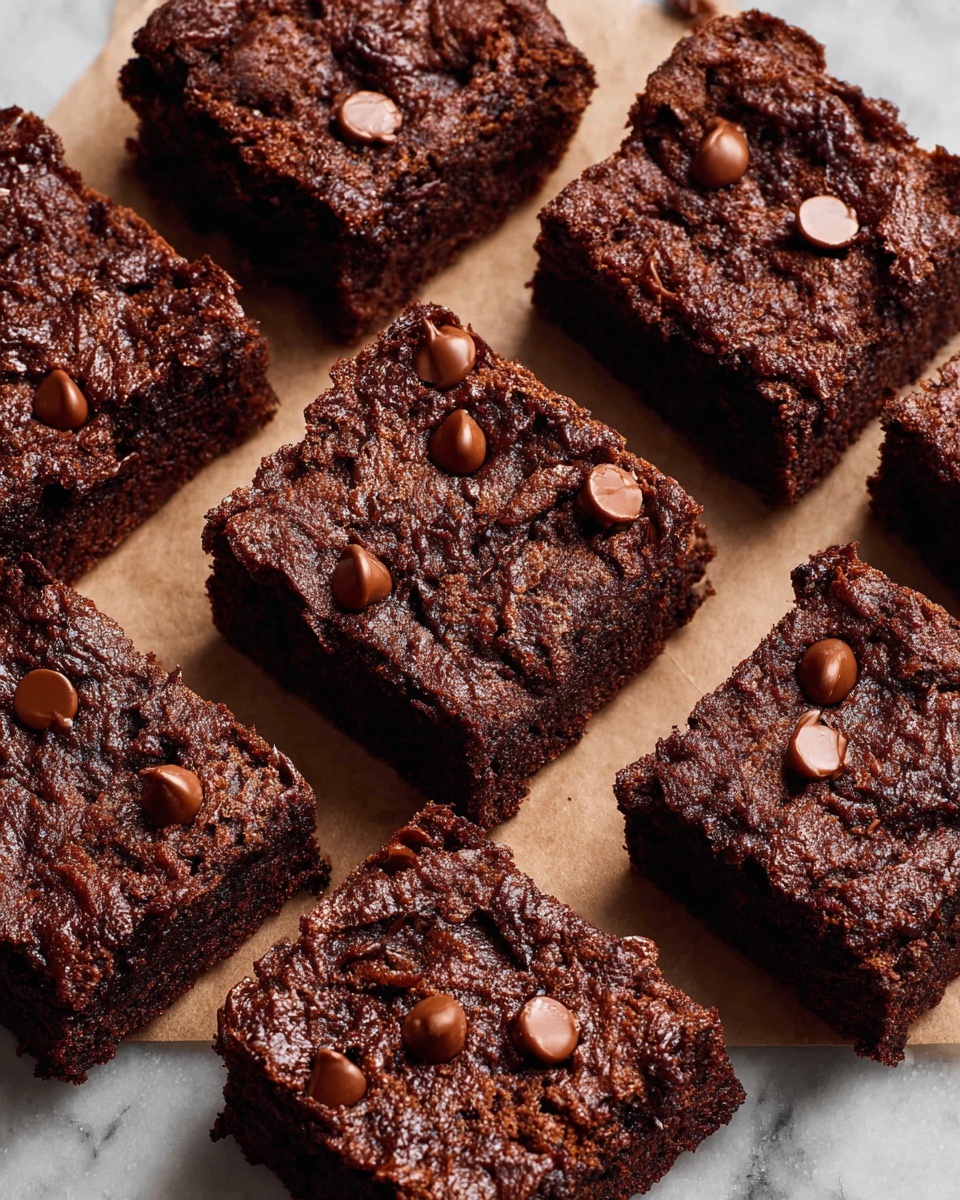 A group of thick, square-shaped chocolate brownies is arranged on parchment paper over a white marbled surface. Each brownie has a rough, textured top with a dark brown color and is studded with scattered milk chocolate chips that add a smooth, shiny contrast. The brownies are cut into uniform pieces and placed close together, showing their dense and moist dough. The chocolate chips are slightly melted and look soft, scattered unevenly on top of each brownie. photo taken with an iphone --ar 4:5 --v 7