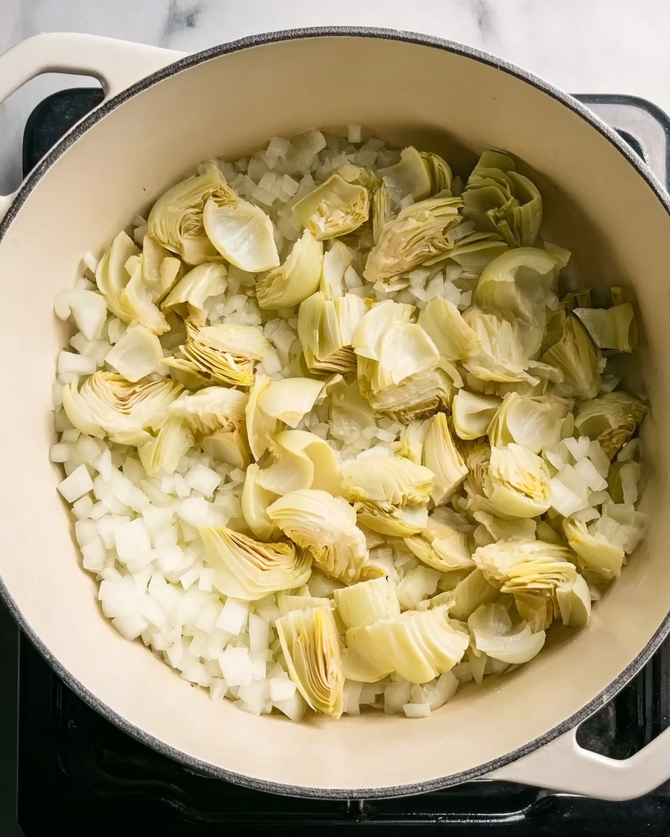 The image shows a white enamel pot filled with chopped onions and sliced artichoke hearts. The onions are small, diced white pieces scattered evenly at the bottom, while the artichoke hearts are light yellowish-green, layered on top with a soft texture. The pot sits on a black stove, and the background is a white marbled surface, creating a clean and bright kitchen atmosphere. photo taken with an iphone --ar 4:5 --v 7
