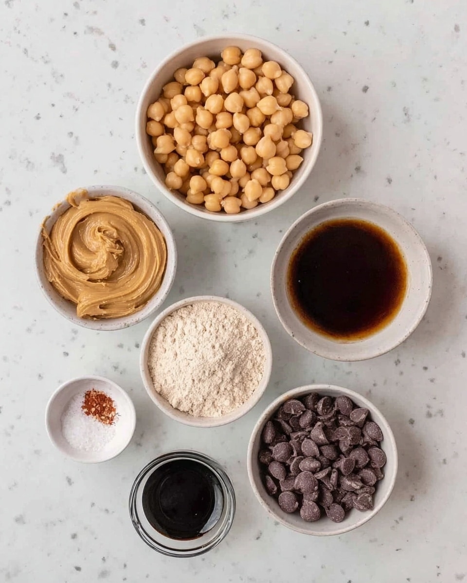 The image shows seven small white bowls placed neatly on a white marbled surface. The top bowl is filled with light brown chickpeas. Below to the left, a bowl holds smooth, light beige peanut butter with a swirled texture on top. To the right of it, a bowl contains dark brown liquid, likely syrup or molasses, with a shiny surface. Below these, in the center, a bowl is filled with light beige flour powder. To the bottom left, a tiny bowl has white salt mixed with a small red spice. In the very front center, a small bowl contains a dark thick liquid, possibly vanilla extract. Lastly, to the bottom right, a bowl is filled with dark brown chocolate chips. The arrangement is clean and organized. photo taken with an iphone --ar 4:5 --v 7
