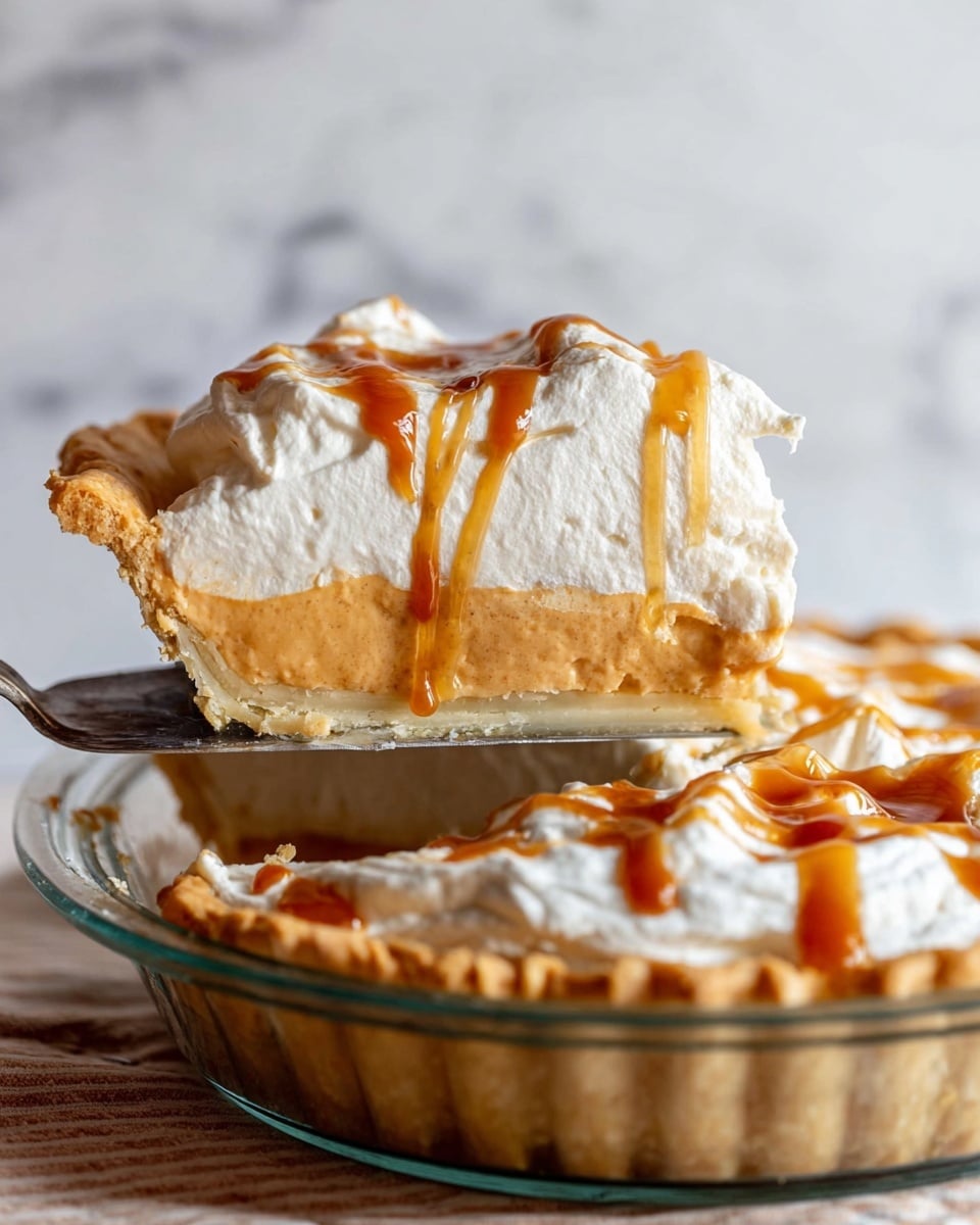 A slice of pie is lifted on a pie server above a glass pie dish that holds the rest of the pie. The pie has three main layers: at the bottom, a golden-brown crust that looks flaky; in the middle, a smooth, light orange filling with a creamy texture; on top, a thick, white whipped cream layer drizzled with caramel sauce that adds a shiny amber color. The crust edges are slightly wavy and golden, giving a homemade look. The background is a white marbled surface, and the focus is on the slice being lifted, showing the clear layers and soft textures. Photo taken with an iphone --ar 4:5 --v 7