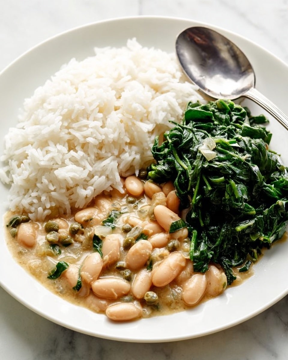 A white plate holds three sections of food placed side by side: on the left, a mound of white rice with a soft, fluffy texture; in the middle, a creamy beige bean stew with small chopped onions and green capers visible in the sauce; on the right, a pile of cooked dark green leafy spinach with a slightly shiny surface. A silver spoon rests on the right edge of the plate, and the whole scene is set on a white marbled surface. photo taken with an iphone --ar 4:5 --v 7