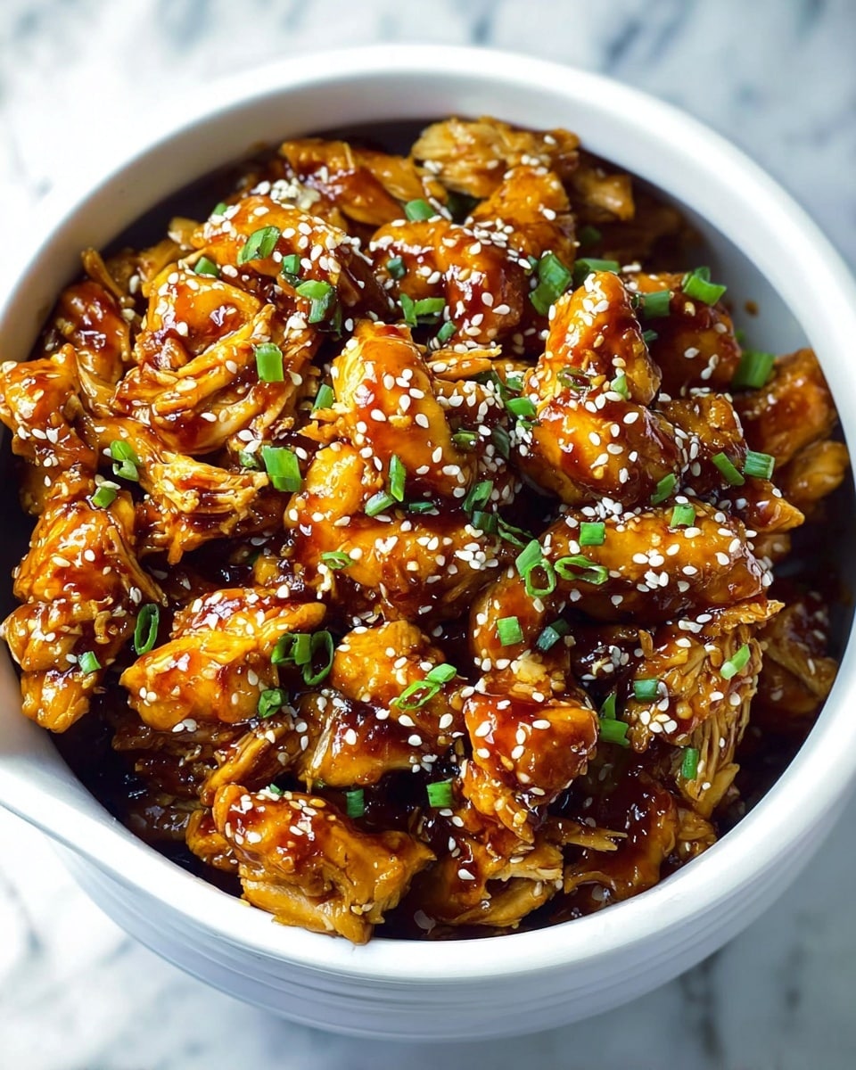 A white bowl filled to the top with shredded golden brown chicken pieces coated in a shiny dark brown sauce, sprinkled evenly with white sesame seeds and small chopped green onions, all resting on a white marbled surface. Photo taken with an iphone --ar 4:5 --v 7