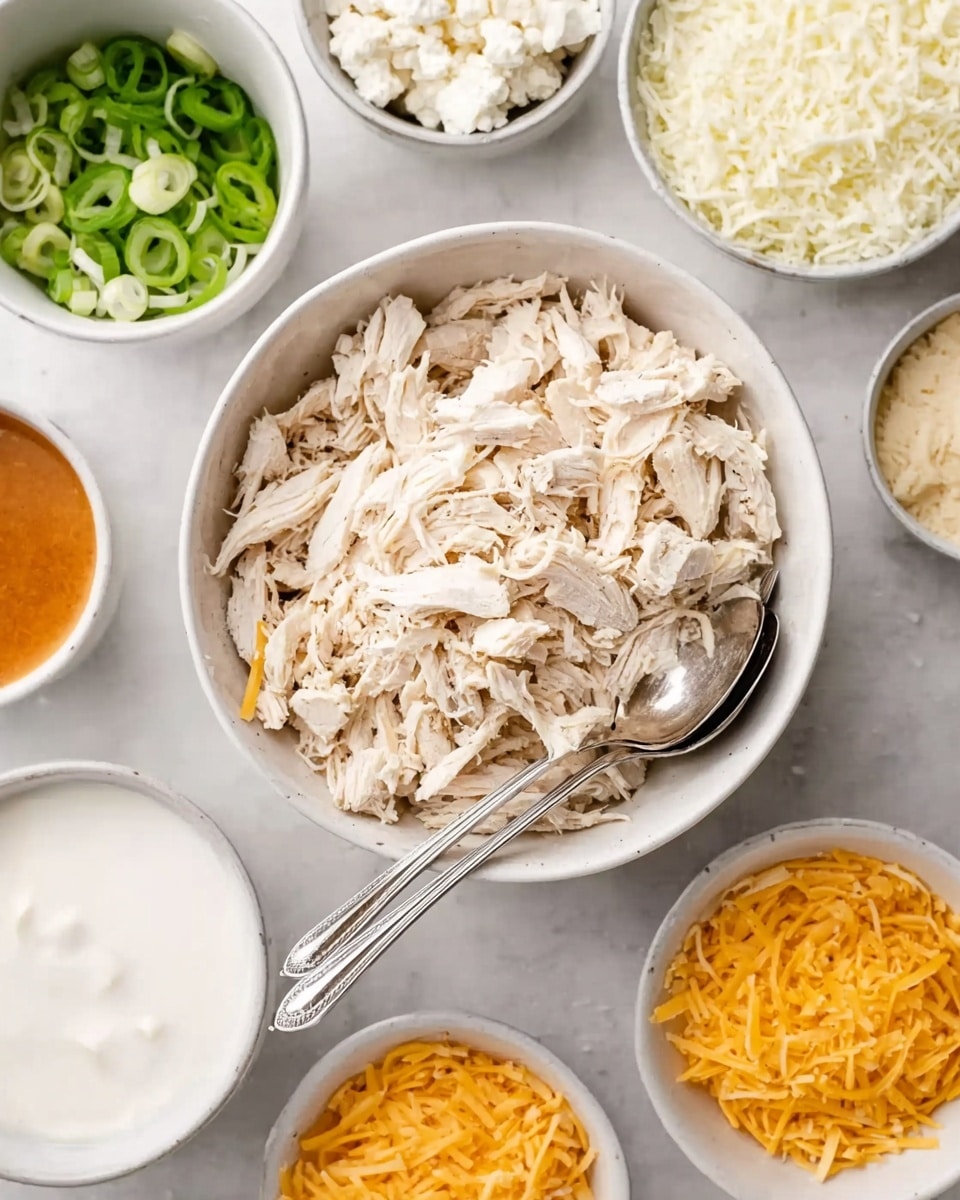 A white bowl in the center filled with shredded white chicken with two silver spoons resting inside. Surrounding the bowl are smaller white bowls arranged in a circle on a white marbled surface. The smaller bowls contain different ingredients: at the top, shredded white cheese; to the right, thinly sliced green onions; further right, a small bowl of white sauce; lower right, shredded yellow cheddar cheese; bottom left, a bowl of white sour cream; lower left, a small bowl with an orange sauce; and to the left, crumbled white cheese. The overall image is bright and neatly arranged with a clean look. Photo taken with an iphone --ar 4:5 --v 7