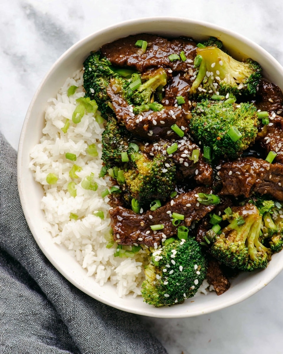 A white bowl filled with a stir-fry dish next to white rice on one side, showing about three layers: a bottom layer of plain white rice with fluffy texture, a middle layer of bright green broccoli florets with a slightly shiny surface, and a top layer of dark brown slices of beef coated with a glossy sauce, sprinkled with white sesame seeds and chopped green onions scattered evenly across the dish. The bowl sits on a white marbled surface with a gray cloth napkin partially visible on the side. Photo taken with an iphone --ar 4:5 --v 7