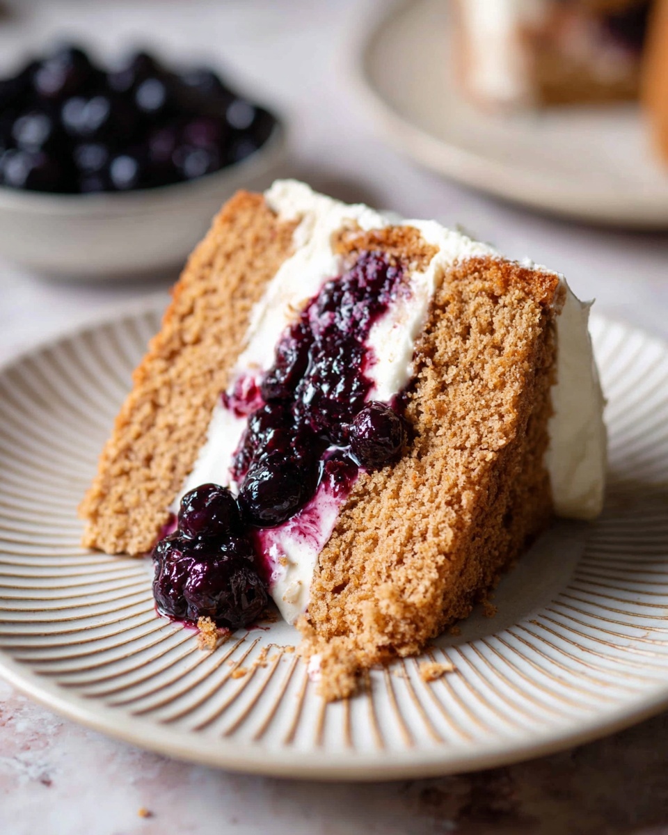 A slice of two-layer light brown cake sits on a white plate with a ridged pattern. Between the layers is a dark purple berry jam, which also covers part of the top layer. On top of the cake, there is a layer of white cream visible. The texture of the cake looks soft and moist, and some whole dark berries are mixed into the jam. The plate is placed on a white marbled surface, with more dark berries slightly out of focus in the background. photo taken with an iphone --ar 4:5 --v 7