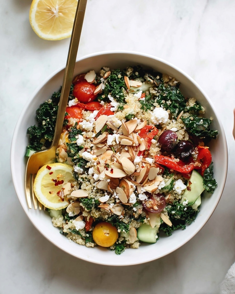 A white bowl filled with a colorful salad showing multiple layers: the base consists of dark green kale leaves and light beige quinoa grains mixed closely together, topped with scattered chunks of red roasted pepper, bright yellow and red cherry tomato halves, and irregular pieces of pale green cucumber. On top of this are thin, toasted almond slices in a light brown shade spread evenly, white crumbled cheese sprinkled throughout, and small bits of dark purple olives. A thin round slice of lemon with red pepper bits sits near the center, adding a bright yellow touch. A gold fork and spoon rest inside the bowl on the left side, all placed on a white marbled surface. Photo taken with an iphone --ar 4:5 --v 7