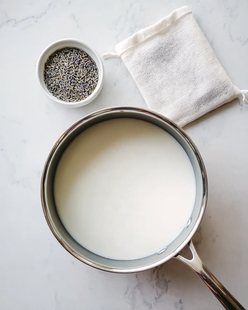 The image shows a stainless steel pot filled with white milk placed on a white marbled surface. Above the pot, there is a small white bowl containing dried lavender buds and an empty small white cloth bag lying flat next to it. The setup is simple and tidy, with the pot in the lower right half and the bowl and cloth bag close to the top left corner. Photo taken with an iphone --ar 4:5 --v 7