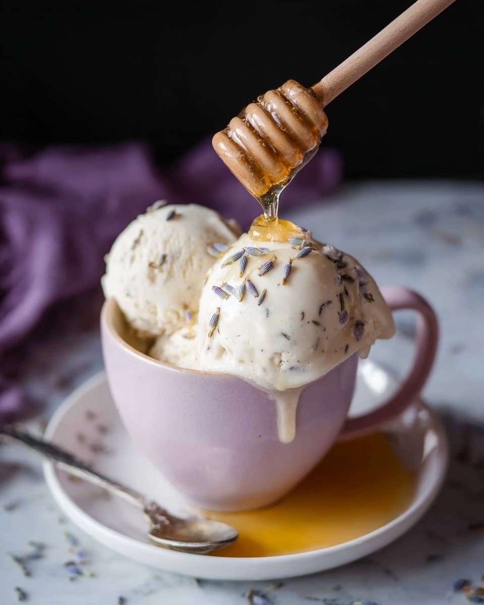 A pink cup filled with three large scoops of creamy white ice cream, with small lavender pieces sprinkled on top. Golden honey is being poured onto the ice cream from a wooden honey dipper, with some honey dripping down the side of the cup onto a white plate below. A spoon with some honey rests on the white plate beside the cup, which sits on a white marbled surface. The background is dark and blurred, putting focus on the ice cream and honey. photo taken with an iphone --ar 4:5 --v 7