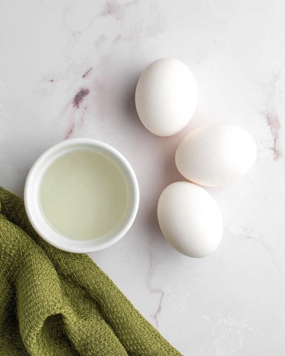 The image shows four smooth white eggs arranged closely together on a white marbled surface. Next to them is a small white bowl filled with a clear liquid, positioned toward the lower left side of the image. At the bottom right corner, there is a textured green cloth partially visible, adding a splash of color to the simple, clean scene. The lighting is soft and natural, highlighting the gentle curves and smooth surfaces of the eggs and bowl. Photo taken with an iphone --ar 4:5 --v 7