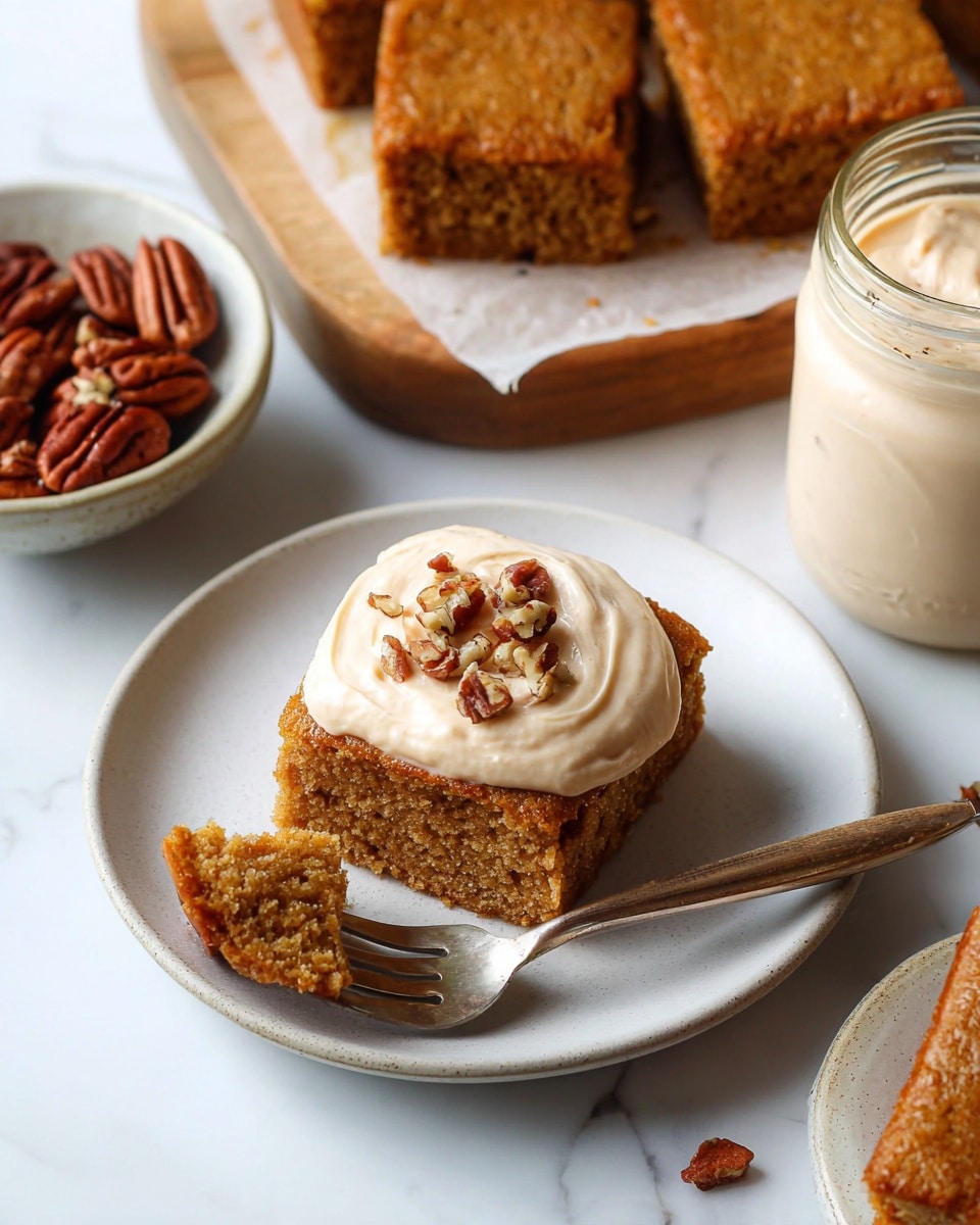 A square piece of moist light brown cake sits on a white plate with a dollop of light tan cream topped with chopped pecans in the center of the cake. A fork on the plate holds a small bite of the cake showing its soft texture. To the upper left, more cake squares rest on a wooden board with parchment paper under them. To the left, a small bowl filled with whole pecans is slightly visible. On the right side, a glass jar filled with the same cream sits partially in the frame. The surface is a white marbled texture. Photo taken with an iphone --ar 4:5 --v 7