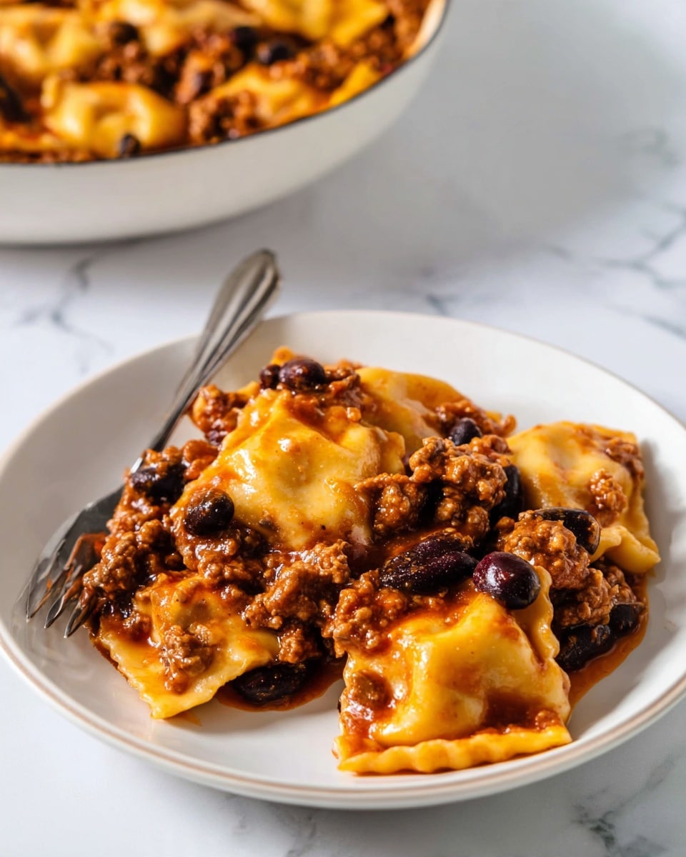 The image shows a white plate filled with several pieces of ravioli pasta layered with a thick reddish-brown sauce mixed with ground meat and whole black beans. The ravioli pieces are soft and slightly glossy, with a pale yellow color, some showing their filling inside. The sauce coats the pasta and meat mixture evenly, creating a rich, hearty texture on top. A metal fork is resting on the plate, slightly under a few ravioli pieces. In the background, a white bowl filled with more of the same dish is partially visible, placed on a white marbled surface photo taken with an iphone --ar 4:5 --v 7